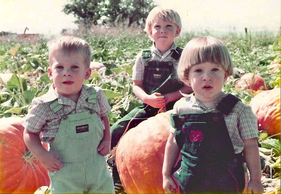 old photo of three children sitting in pumpkin patch