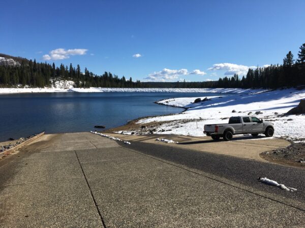 boat ramp into a lake in winter with snow covered forest in background