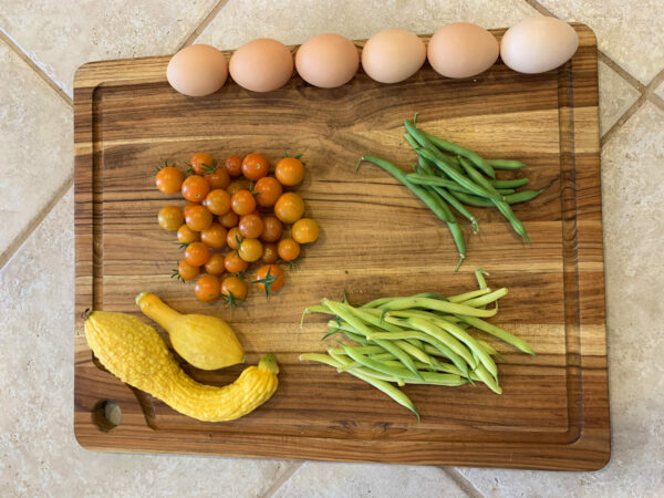 cutting board with eggs, tomatoes, squash, and beans