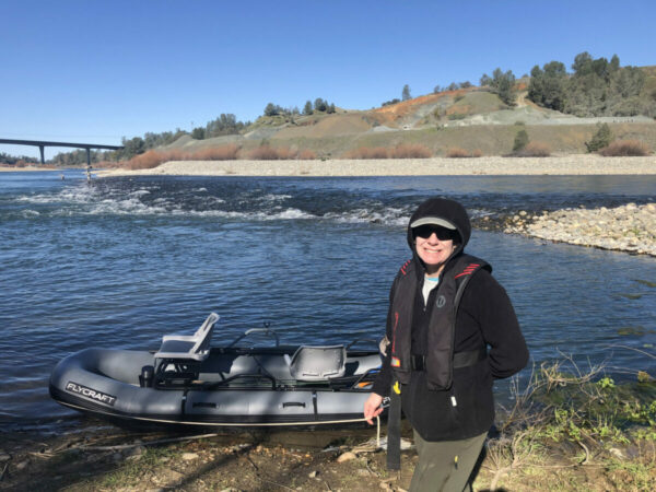 woman standing next to a boat on the shore of the yuba river